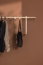 Garderobe TAMINA mit minimalistischen Metallstangen, an der Wand montiert, mit Kleidung zum Aufhängen.