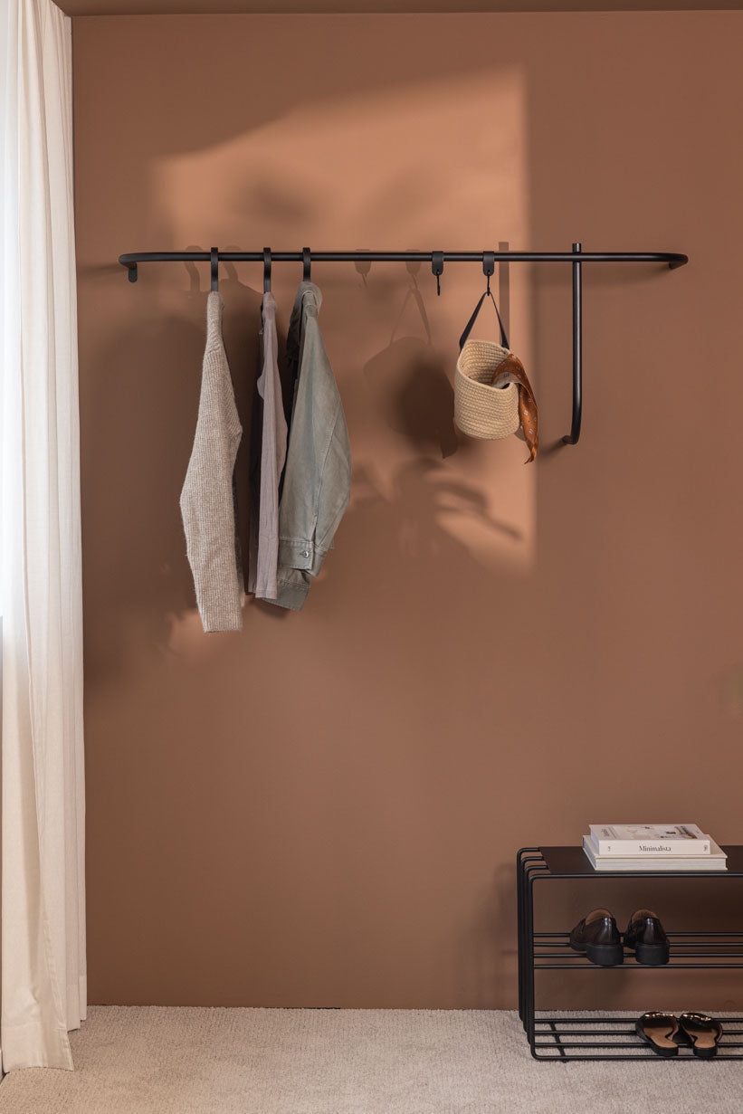 Moderne Garderobe TAMINA mit minimalistischer Aufhängung für Kleidung und Accessoires an einer Wand.