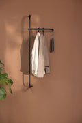 Moderne Garderobe TAMINA aus Metall mit Kleidung an der Wand montiert.