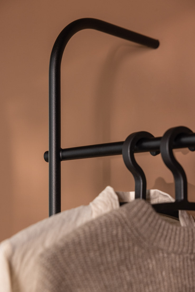 Garderobe TAMINA mit minimalistischen Metallstangen und Kleidungsstücken zum Aufhängen.
