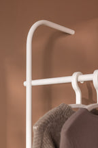 Detailansicht der Garderobe TAMINA mit eleganten Metallstangen und aufhängenden Kleidungsstücken.