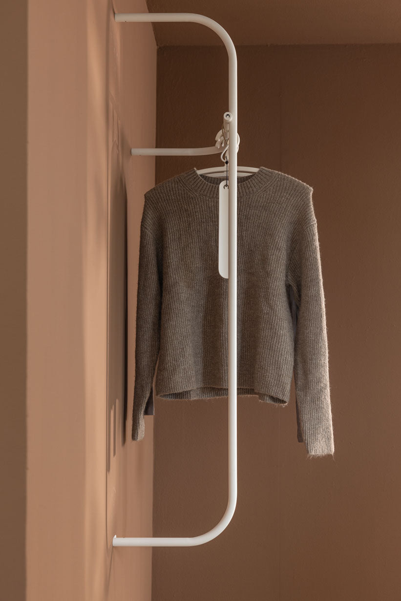 Moderne Garderobe TAMINA mit einem grauen Pullover auf einem minimalistischen Kleiderbügel.