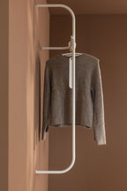 Moderne Garderobe TAMINA mit einem grauen Pullover auf einem minimalistischen Kleiderbügel.
