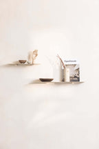 Modernes Wandregal LENN aus Metall mit dekorativen Objekten und einem Magazin an der Wand.