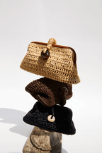 Stack of three artisan-crafted pouch bags made from natural raffia in umber tones.