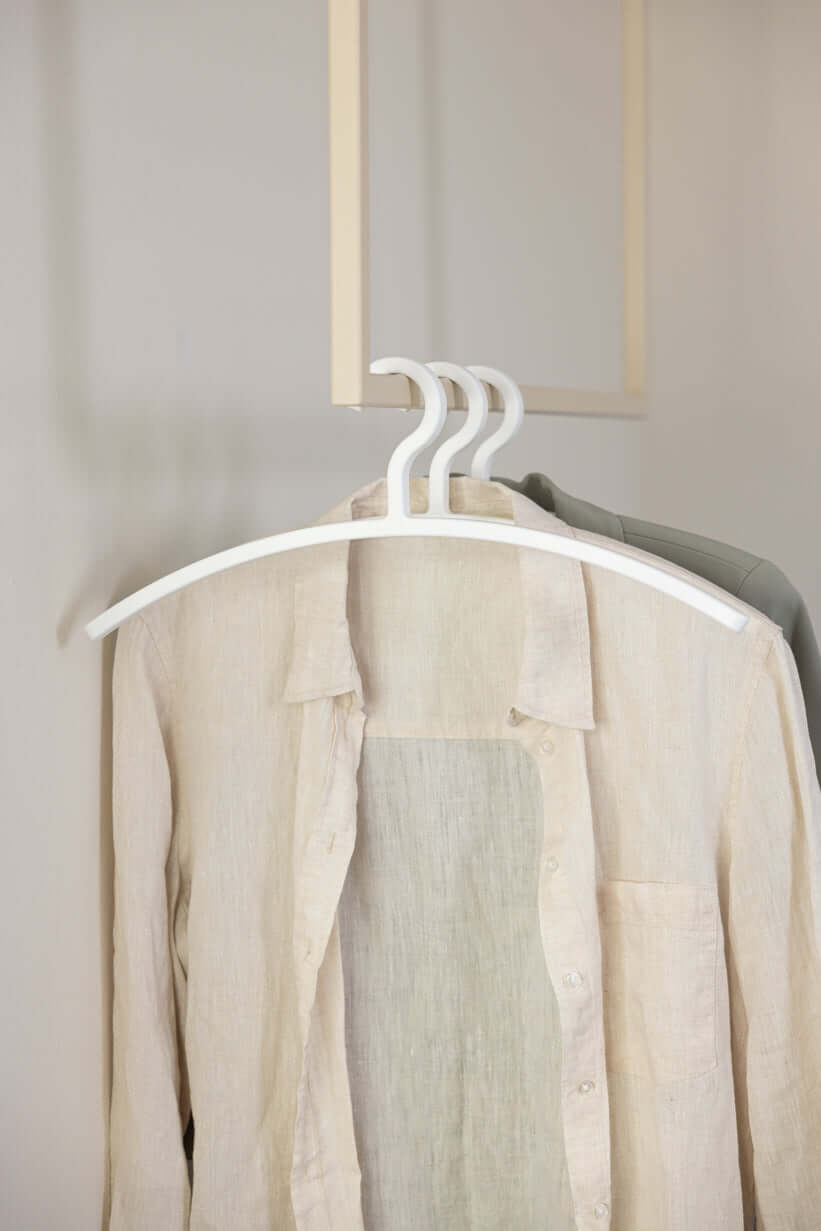 Kleiderbügel FAY im minimalistischen Design mit zwei Hemden auf weißen Kleiderbügeln hängend.