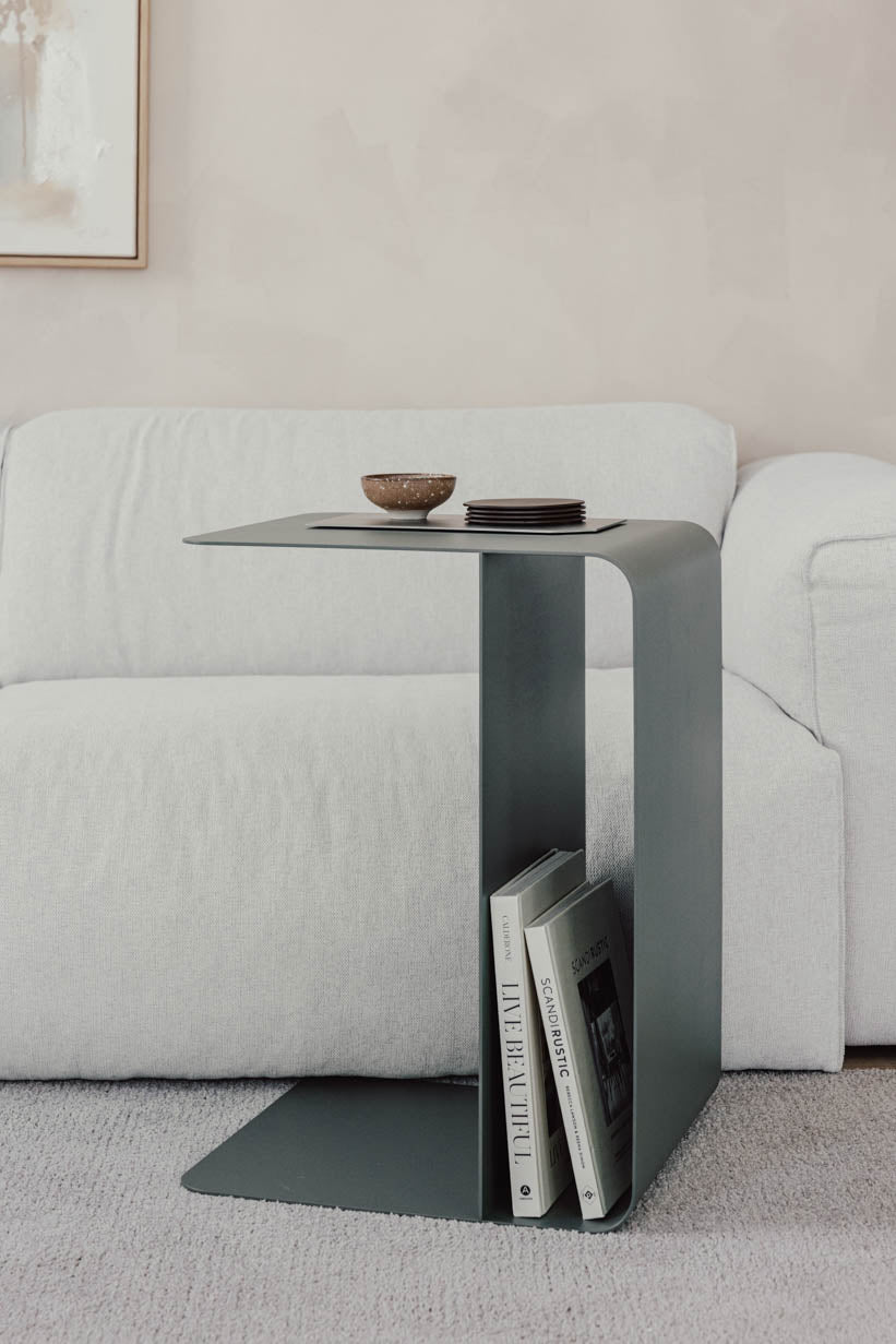 Beistelltisch COSMO aus pulverbeschichtetem Metall neben einem Sofa mit Zeitschriften und Geschirr.