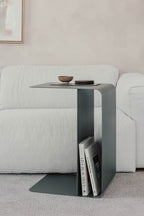 Beistelltisch COSMO aus pulverbeschichtetem Metall neben einem Sofa mit Zeitschriften und Geschirr.