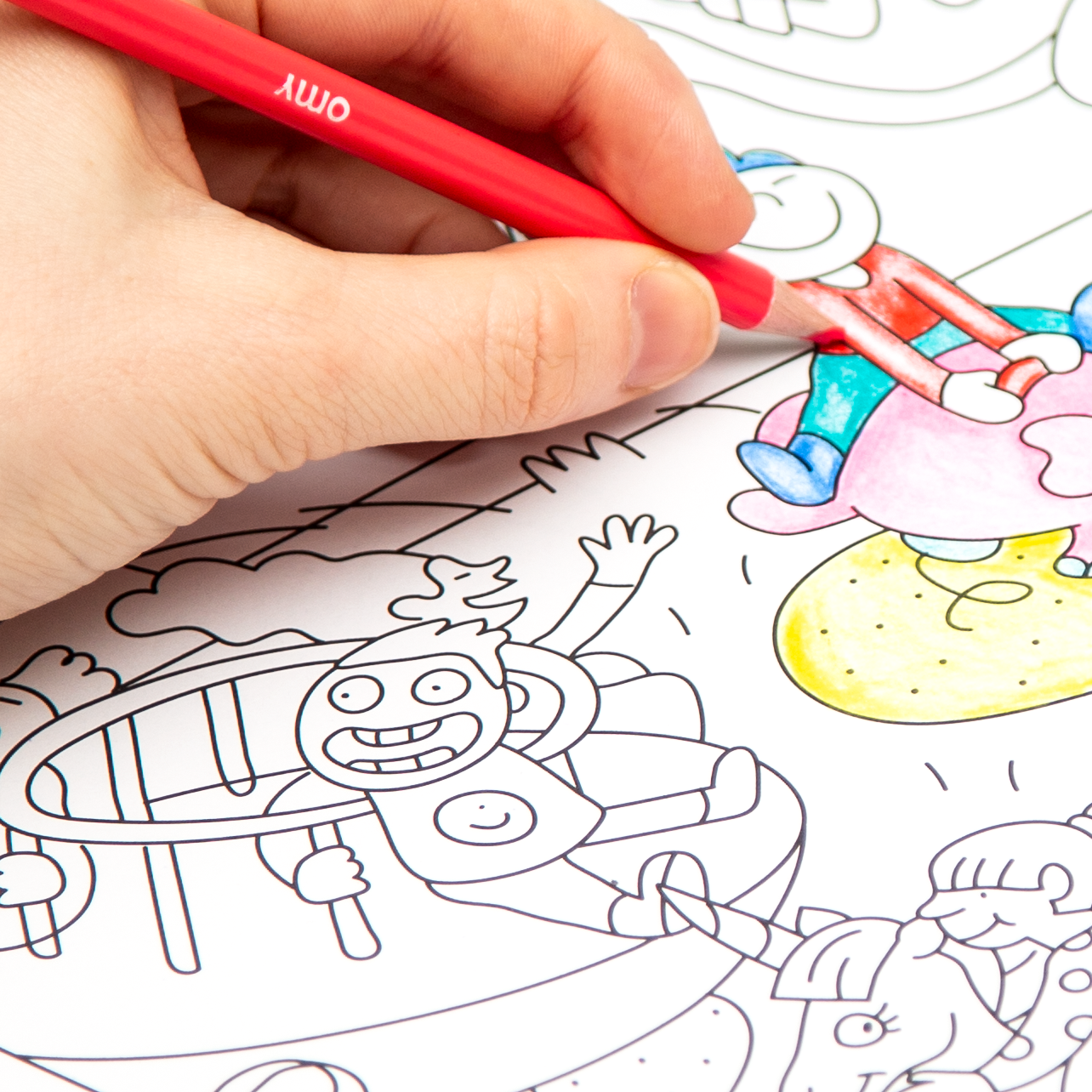 Main d'enfant coloriant le poster "Kids Life" OMY avec des feutres rouges