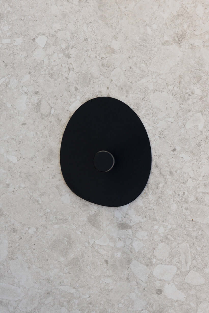 Küchenrollenhalter IVANA in elegantem schwarzem Design auf einer hellen Steinoberfläche.