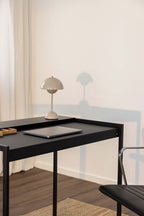 Schreibtisch DONNA mit Schreibtischlampe und Laptop auf schwarzem Tisch, ideal für modernes Büro.