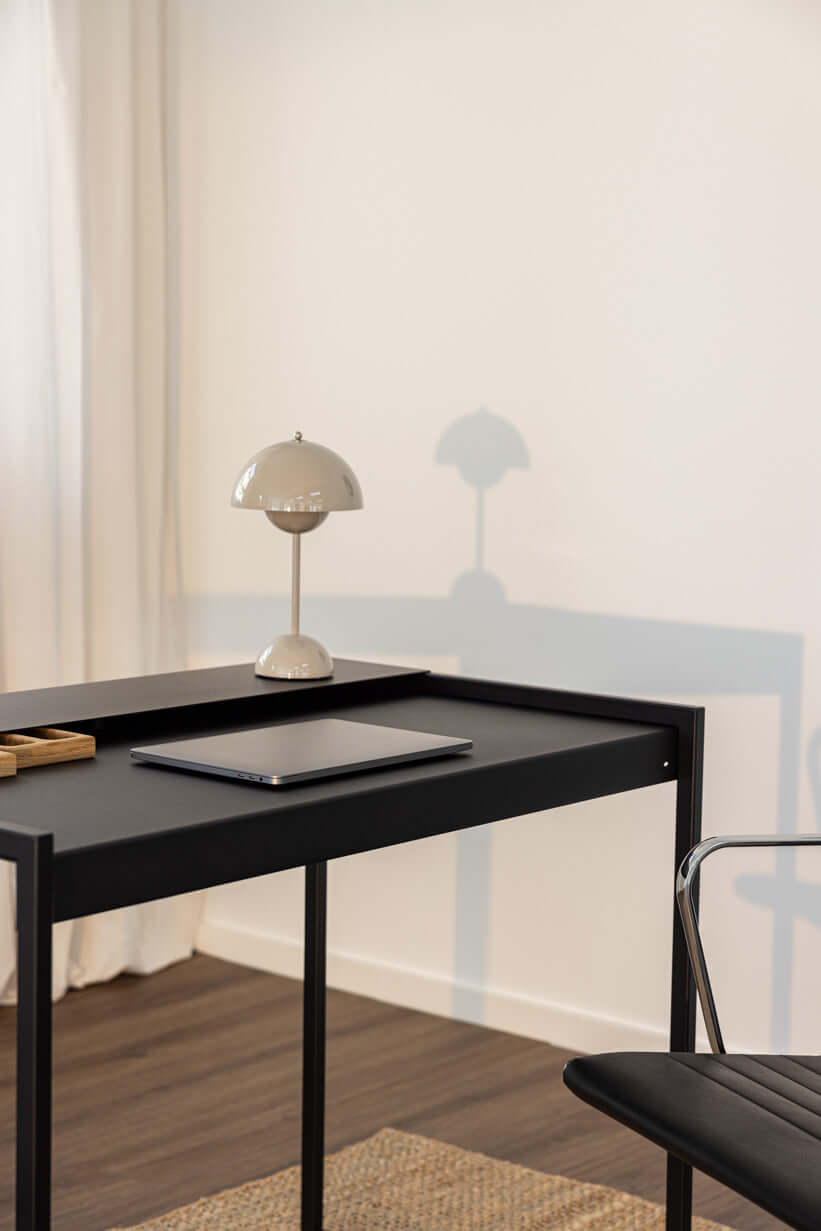 Schreibtisch DONNA mit Schreibtischlampe und Laptop auf schwarzem Tisch, ideal für modernes Büro.