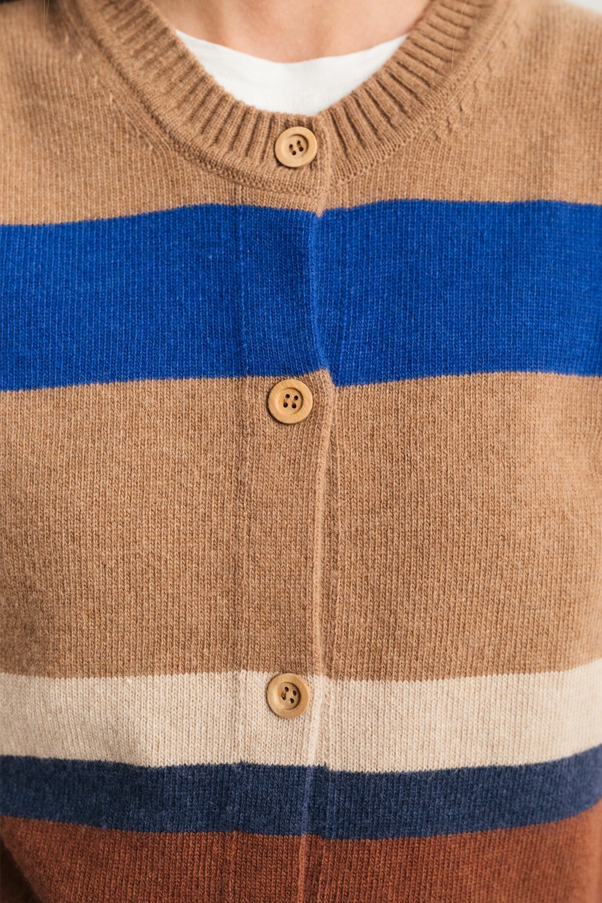 close-up of eco-conscious striped vest with natural wood buttons