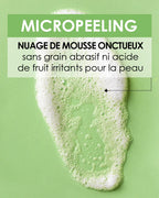 Gros plan sur la texture du Pschitt Magique Garancia : un nuage de mousse onctueux blanc sur fond vert, avec un texte précisant une formule sans grain abrasif ni acide de fruit irritant.