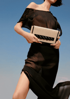 Model showcasing Thory Black Envelope Clutch against a clear sky, embodying sophistication and modern style.