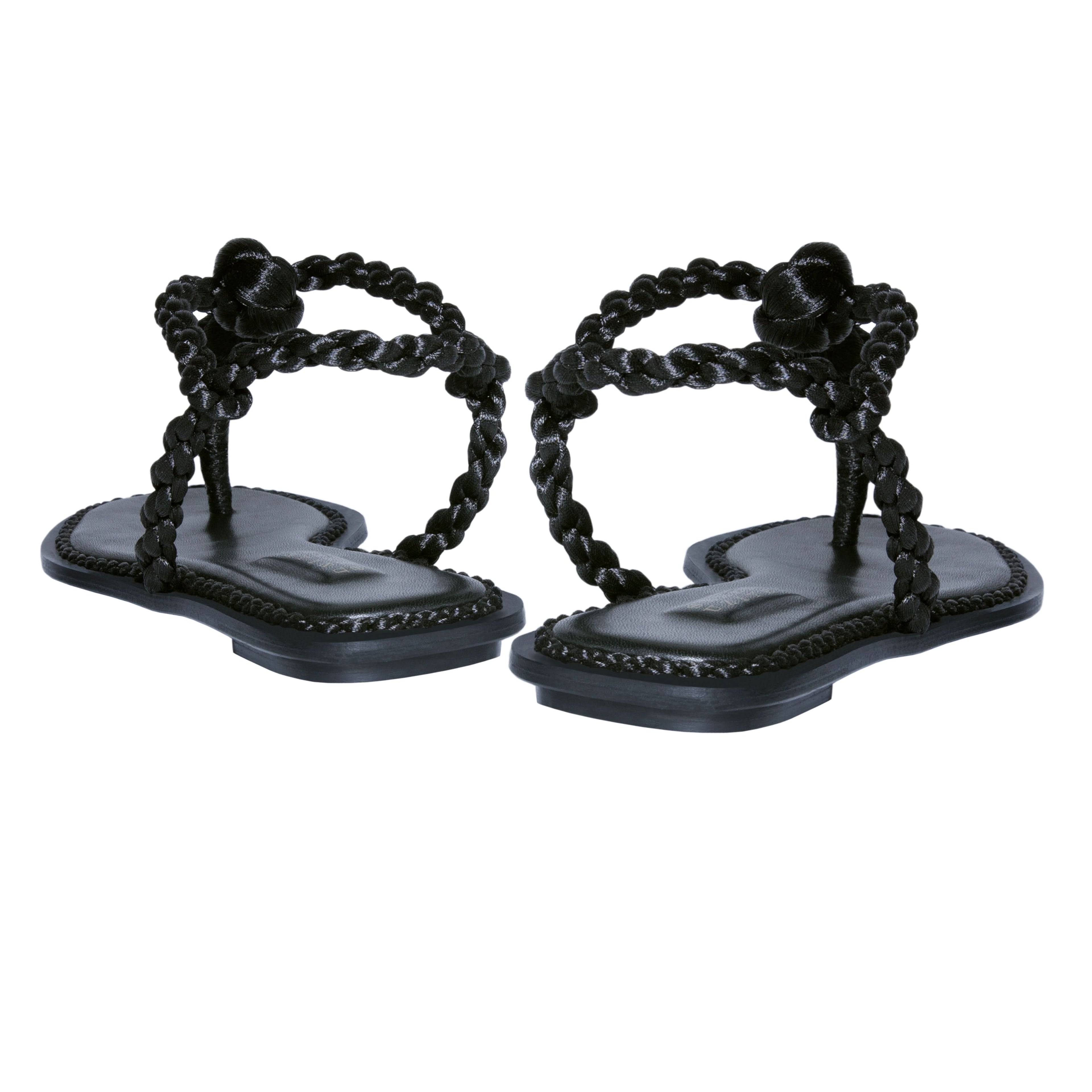 Thory Black Flat Sandal featuring braided metallic thread straps and a rich Italian leather sole for a casual yet elegant look.